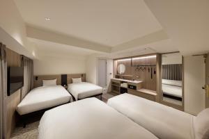 a hotel room with three beds and a sink at the b namba-kuromon in Osaka