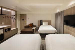 a hotel room with two beds and a couch at the b namba-kuromon in Osaka