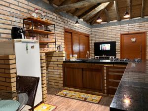 una cucina con frigorifero bianco e TV di Chalé de Pedra a Praia Grande Altre 15 foto