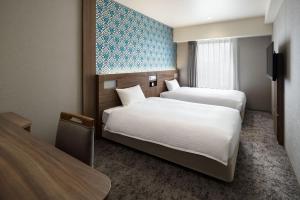 a hotel room with two beds and a tv at the b namba-kuromon in Osaka