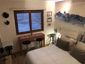 a bedroom with a bed and a window and a table at Departamento residencial Valle Nevado in Lo Barnechea