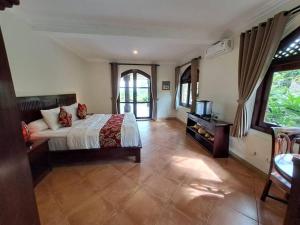 1 dormitorio con 1 cama y TV. en Dzawani Villa Ubud, en Tampaksiring