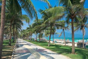 a sidewalk lined with palm trees next to the beach at NALINI Hotel & Apartment in Da Nang