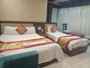 DhuburiにあるThe Brahmaputra Hotelのベッド2台とソファが備わるホテルルームです。