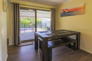 uma mesa de madeira num quarto com uma janela em Hibiscus Holiday Home em Urangan