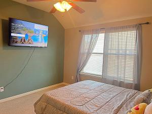 um quarto com uma cama e uma televisão de ecrã plano em Cozy luxury home em Grand Prairie