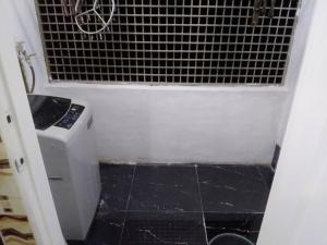 uma pequena casa de banho com piso em azulejo preto e uma máquina de lavar roupa em Homestay Legacy Yumai Kuala Rompin em Kuala Rompin