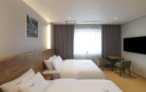 um quarto de hotel com duas camas e uma televisão em Hotel Grand Bay Boryeong em Boryeong