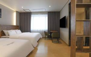 a hotel room with two beds and a television at Hotel Grand Bay Boryeong in Boryeong
