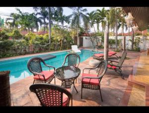 un grupo de sillas y mesas junto a una piscina en Siri Villa en Jomtien Beach