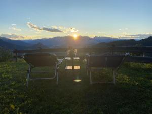 una mesa y sillas sentadas en el césped con la puesta de sol en Nostalgie di un tempo nelle Dolomiti, en Pergine Valsugana