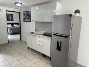 a kitchen with a refrigerator and a room with a bed at Casa Mel, Excelente ubicacion, seguridad in Cozumel