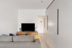 a living room with a couch and a tv at Urban Rest North Sydney Apartments in Sydney
