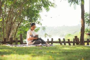 Una donna seduta sull'erba che guarda una telecamera di An Homestay a Di Linh