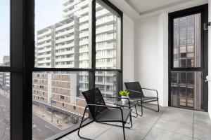 two chairs and a table in a room with large windows at Urban Rest North Sydney Apartments in Sydney