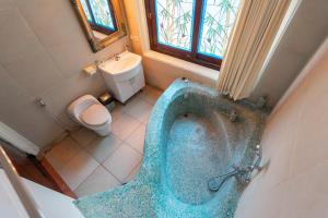 La salle de bains est pourvue d'une baignoire bleue et de toilettes. dans l'établissement Dzawani Ubud, à Tampaksiring