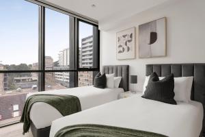 two beds in a bedroom with a large window at Urban Rest North Sydney Apartments in Sydney