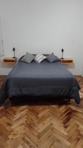 1 cama con manta negra en el suelo de madera en departamento en almagro, 2 huéspedes en Buenos Aires