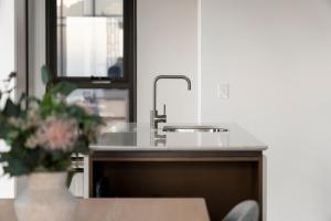 a kitchen counter with a sink and a vase of flowers at Urban Rest North Sydney Apartments in Sydney
