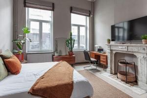 1 dormitorio con cama, escritorio y chimenea en Comenstay Brussels, en Bruselas