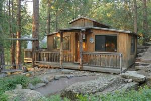 a wooden cabin in the woods with a stream at Eagles Nest - Natural Log Cabin with Guest House in Idyllwild