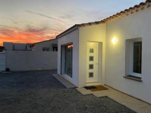 uma casa branca com o pôr-do-sol ao fundo em JOLIE MAISON A 700M DE LA MER em Le Grau-dʼAgde