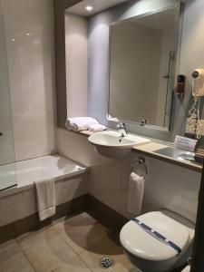 a bathroom with a toilet and a sink and a mirror at Off Broadway Motel in Auckland +21 photos
