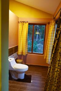 a bathroom with a toilet and a window at Atulya Kanchi Camp Bandhavgarh in Tāla