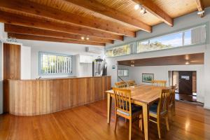 a dining room with a wooden table and chairs at Absolute Blue by Experience Jervis Bay in Hyams Beach