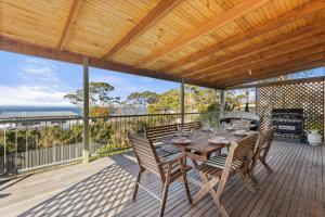 a wooden table and chairs on a deck with a grill at Absolute Blue by Experience Jervis Bay in Hyams Beach