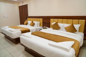 two beds in a hotel room with two beds at Sri Krishna Inn - Kempegowda Airport Bangalore in Bangalore