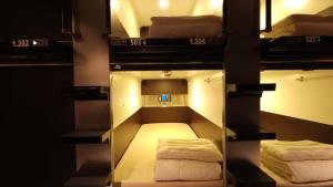 a room with three bunk beds and a mirror at Acro Capsule Hotel Namba Dotonbori in Osaka