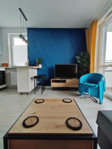 ein Wohnzimmer mit einem Tisch und einer blauen Wand in der Unterkunft Przytulne mieszkanie przy Kanale Żerańskim in Warschau