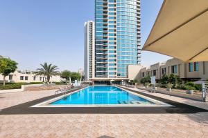 a swimming pool in front of a tall building at ALH Vacay - 2 bedrooms Apartment in Golf Towers 1 in Dubai
