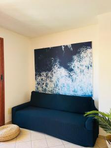 um sofá azul num quarto com uma pintura na parede em Twinfins apartments em Buggerru