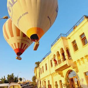 two hot air balloons are flying over a building at Alice in Cappadocia in Uchisar