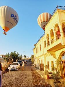 a hot air balloon flying over a street with a building at Alice in Cappadocia in Uçhisar