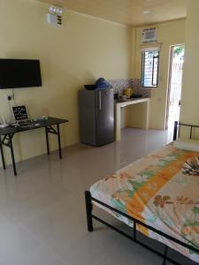 a room with a bed and a table and a refrigerator at Bluewaves Apartment in Dauis