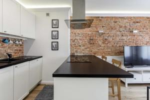a kitchen with white cabinets and a black counter top at Golden Apartments Wrocław&Uniwersytecka in Wrocław