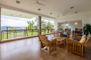 un salon avec une table et des chaises et un balcon dans l'établissement ama Stays & Trails Arcadia, Coorg, à Madikeri