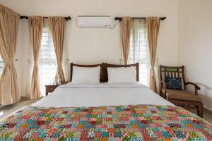 um quarto com uma cama com uma colcha colorida em ama Stays & Trails Arcadia, Coorg em Madikeri