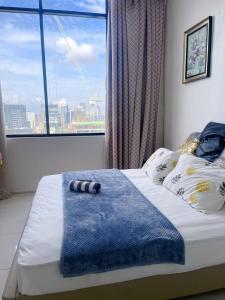 ein Schlafzimmer mit einem Bett mit einer blauen Decke und einem Fenster in der Unterkunft Cebu Aviner(water Front) in Cebu City