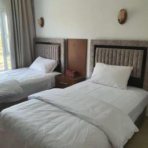 - 2 lits dans une chambre d'hôtel avec des draps blancs dans l'établissement بيوت الخزام, à Salmah