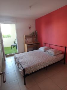 - une chambre avec un lit et un mur rouge dans l'établissement Beau T3 + clim + parking Saint Cyr sur mer, à Saint-Cyr-sur-Mer