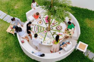 eine Gruppe von Menschen, die um einen Tisch im Gras stehen in der Unterkunft Moodhoian Riverside Resort & Spa in Hoi An