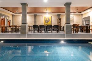 a swimming pool with tables and chairs in a building at Villa Bunga Hotel in Seminyak