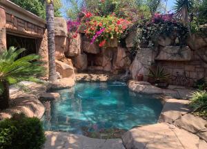 uma pequena piscina com uma parede de pedra e flores em Eagle Rock Executive Guest House em Kempton Park