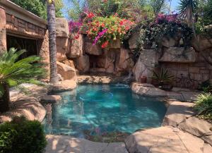 una pequeña piscina con una pared de roca y flores en Eagle Rock Executive Guest House, en Kempton Park