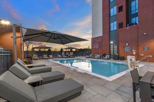 a pool with chairs and an umbrella next to a building at Residence Inn by Marriott Atlanta Covington in Covington