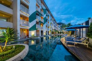 a hotel pool with chairs and an umbrella at Bliss Surfer Hotel by Tritama Hospitality in Legian